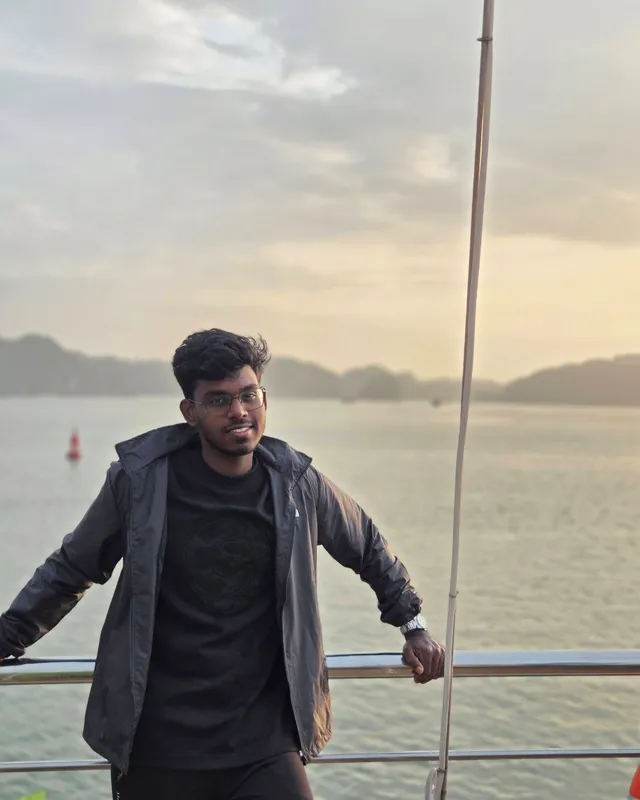 Adheeban Manoharan, leaning on a ship's railing with the sea behind him